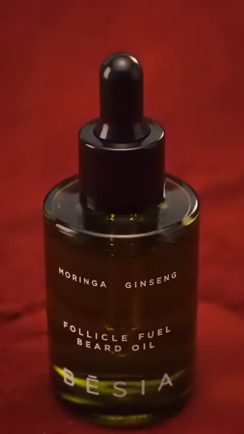 The amber Follicle Fuel Beard Oil bottle on terracotta sand