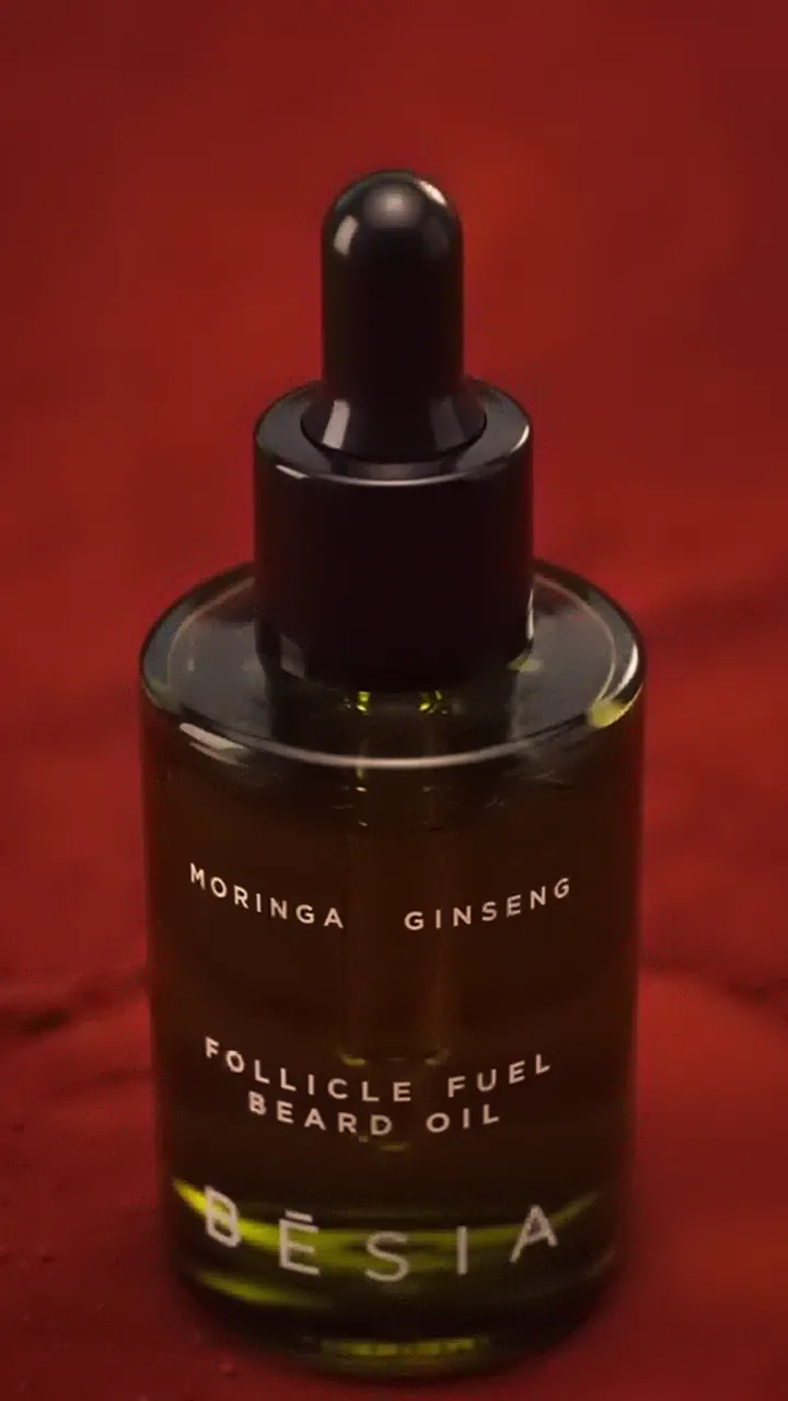 The amber Follicle Fuel Beard Oil bottle on terracotta sand