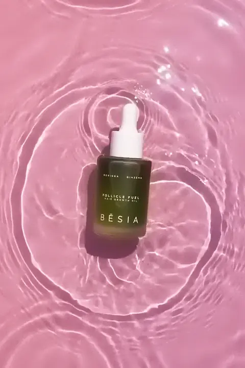 The Follicle Fuel bottle in pink water, ripples