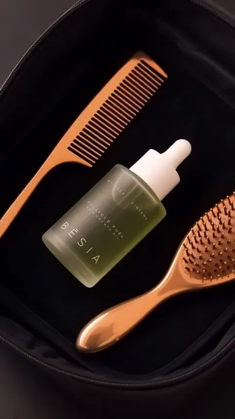 The Follicle Fuel Hair Growth Oil bottle on black velvet beside rose gold combs
